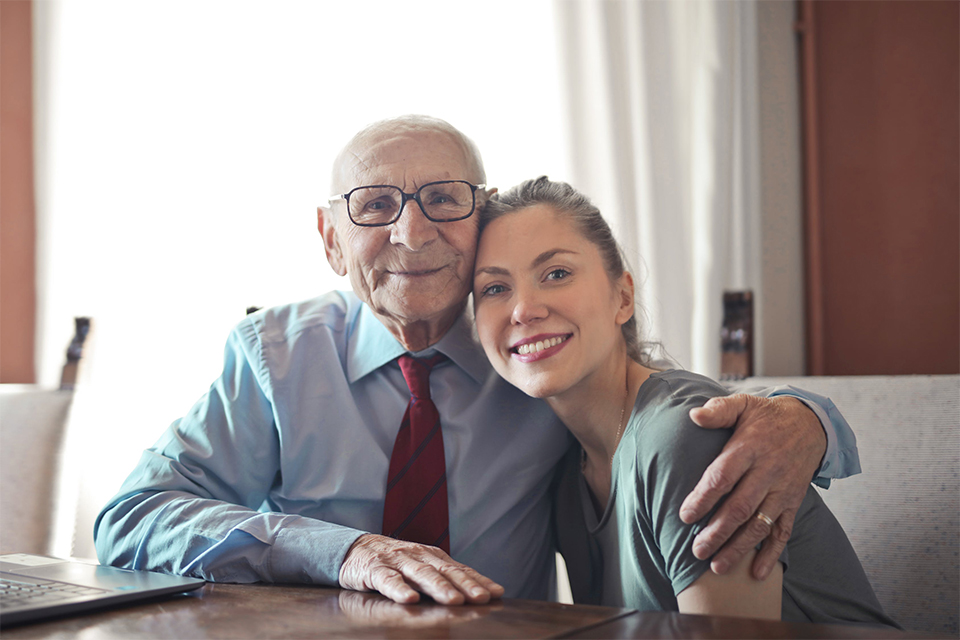 Een bejaarde man en een vrouw kijken lachend naar de camera